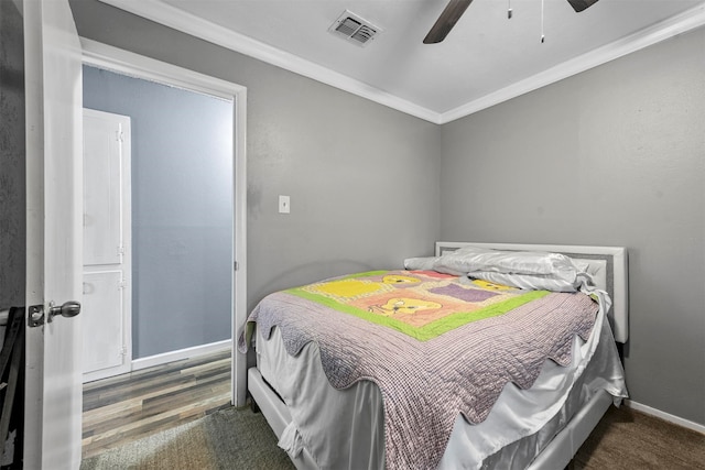 bedroom featuring ceiling fan, crown molding, and dark wood-type flooring