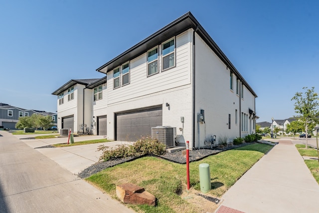 exterior space featuring central AC unit, a garage, and a yard