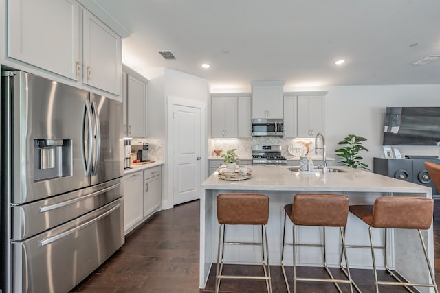 kitchen featuring backsplash, dark hardwood / wood-style floors, an island with sink, and stainless steel appliances