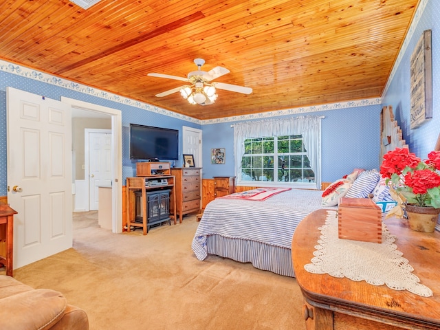 carpeted bedroom featuring ceiling fan, crown molding, a wood stove, and wood ceiling