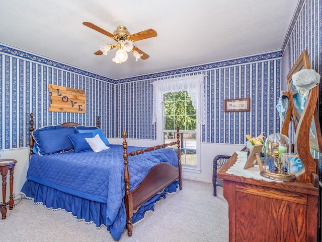 bedroom with a wainscoted wall, ceiling fan, light carpet, and wallpapered walls