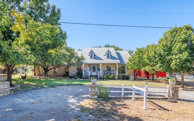 new england style home with a fenced front yard, a front yard, covered porch, and metal roof