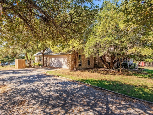 view of front of house with gravel driveway, fence, and brick siding