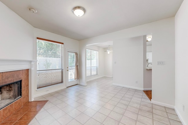 unfurnished living room with light tile patterned flooring, a tile fireplace, and ceiling fan