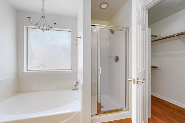 bathroom featuring plenty of natural light, an inviting chandelier, shower with separate bathtub, and hardwood / wood-style flooring