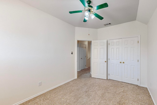 unfurnished bedroom featuring ceiling fan, vaulted ceiling, a closet, and light carpet