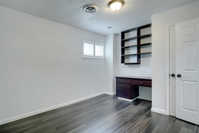 unfurnished office featuring built in desk and dark hardwood / wood-style flooring