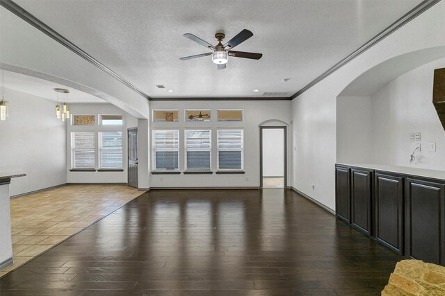 unfurnished living room featuring a textured ceiling, ceiling fan, ornamental molding, and wood-type flooring