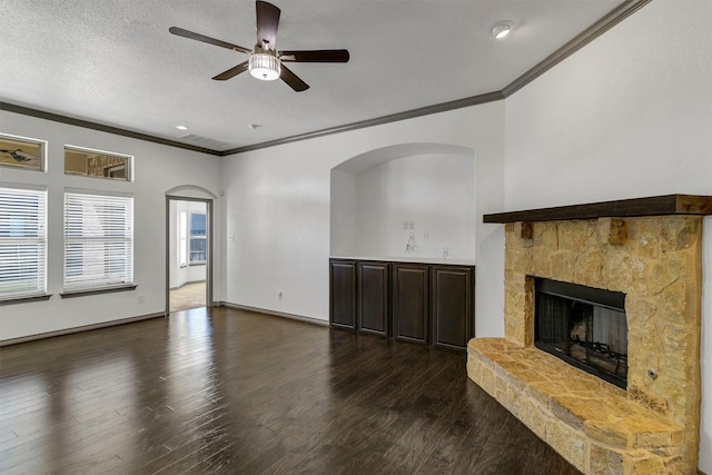 unfurnished living room with dark hardwood / wood-style flooring, ornamental molding, and a stone fireplace