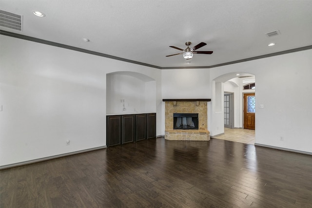 unfurnished living room featuring hardwood / wood-style floors, a stone fireplace, and ornamental molding