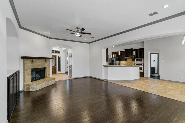 unfurnished living room with a fireplace, ceiling fan, light tile patterned flooring, and ornamental molding