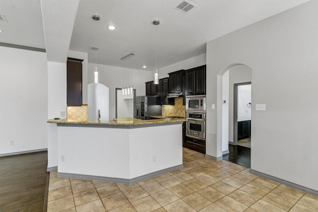 kitchen with backsplash, stainless steel appliances, light hardwood / wood-style flooring, and kitchen peninsula