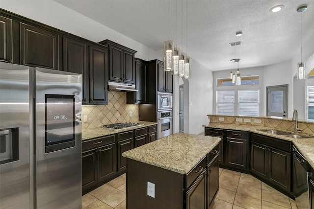 kitchen featuring sink, appliances with stainless steel finishes, tasteful backsplash, a kitchen island, and hanging light fixtures