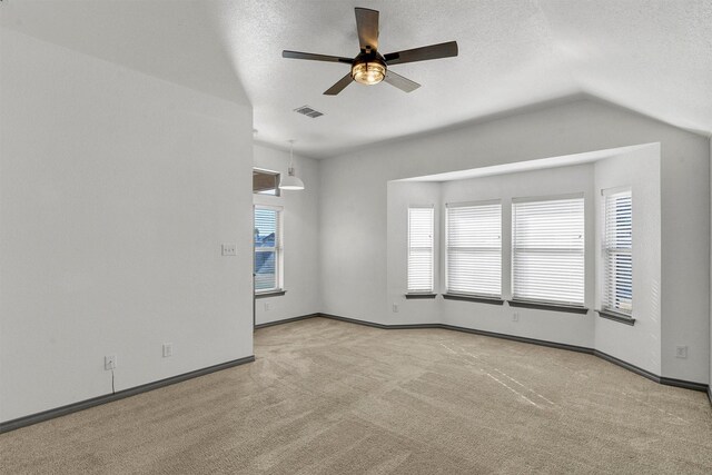 carpeted spare room with ceiling fan, a textured ceiling, and lofted ceiling