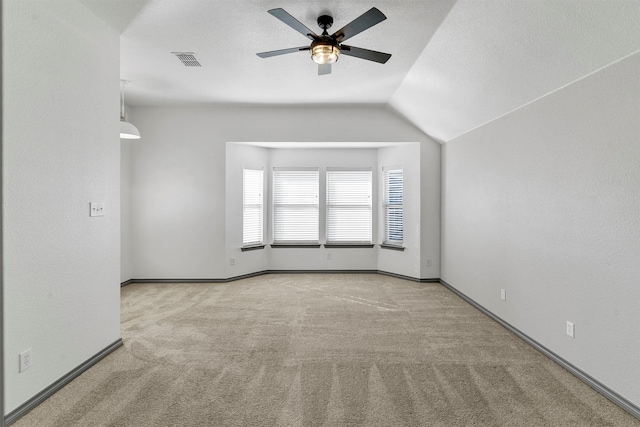 spare room featuring ceiling fan, vaulted ceiling, and light colored carpet