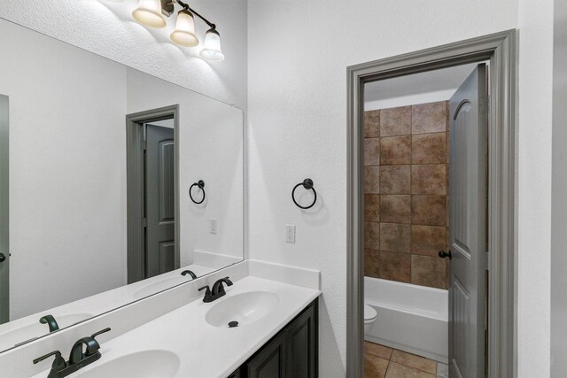 full bathroom featuring toilet, tiled shower / bath combo, vanity, and tile patterned floors