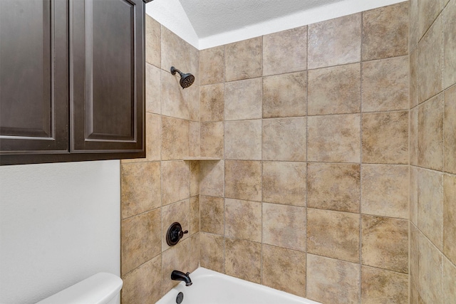 bathroom with tiled shower / bath, a textured ceiling, and toilet