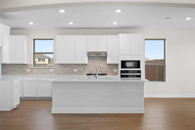 kitchen with white cabinetry, black appliances, and a center island with sink