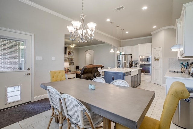 tiled dining area with plenty of natural light, ceiling fan with notable chandelier, and ornamental molding