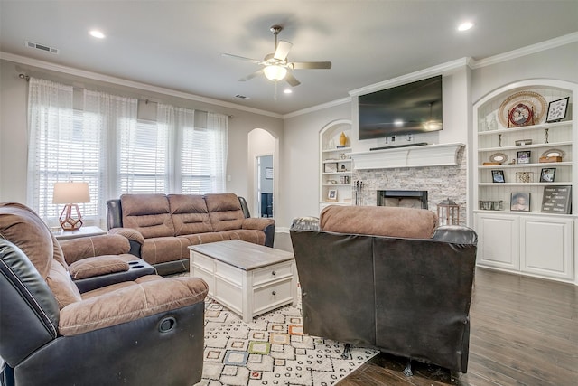 living room with hardwood / wood-style floors, built in features, crown molding, a fireplace, and ceiling fan