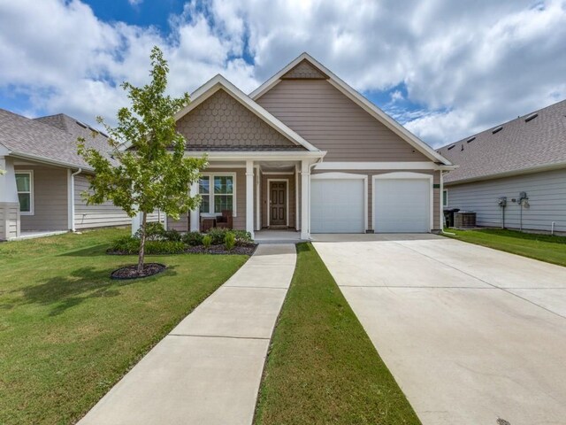 view of front of house featuring a front lawn, a garage, covered porch, and central AC