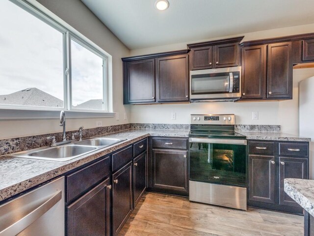 kitchen with stainless steel appliances, light hardwood / wood-style floors, dark brown cabinetry, and sink