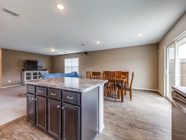 kitchen featuring visible vents, baseboards, open floor plan, light countertops, and stainless steel dishwasher