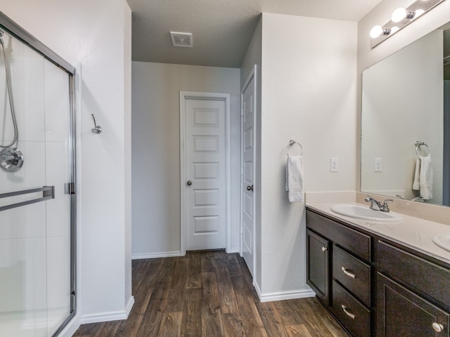 bathroom with a shower with door, vanity, hardwood / wood-style floors, and a textured ceiling