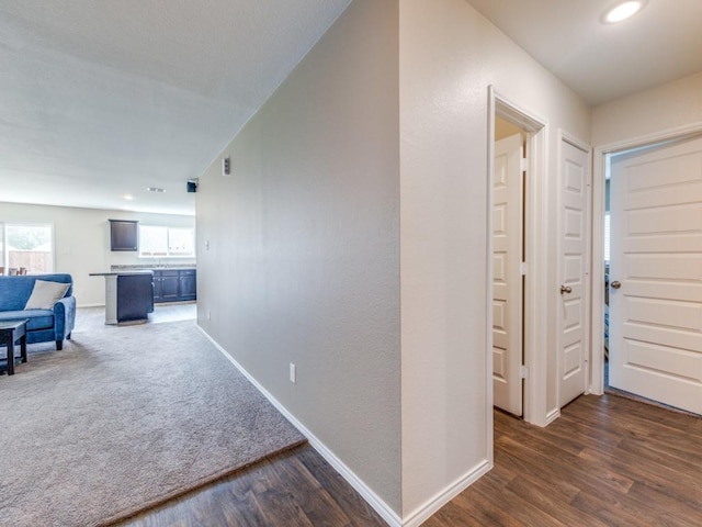 hallway with dark carpet, baseboards, dark wood finished floors, and recessed lighting