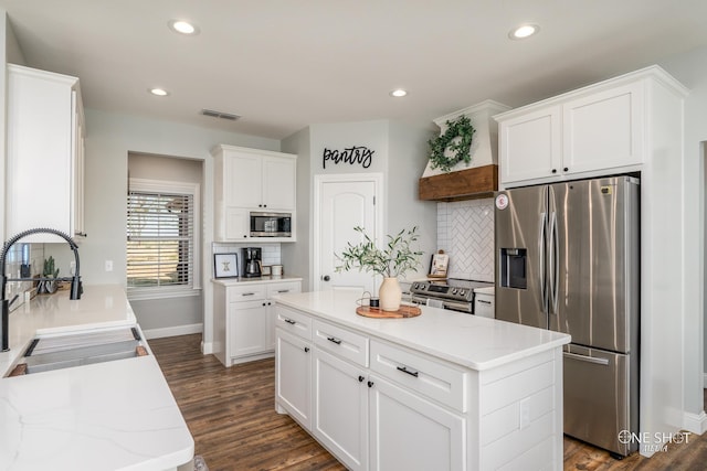 kitchen with visible vents, white cabinets, custom range hood, a center island, and stainless steel appliances