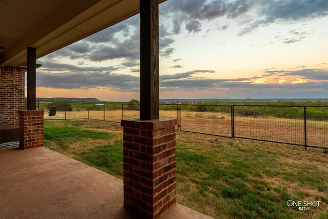 view of yard featuring a patio area, a rural view, and fence