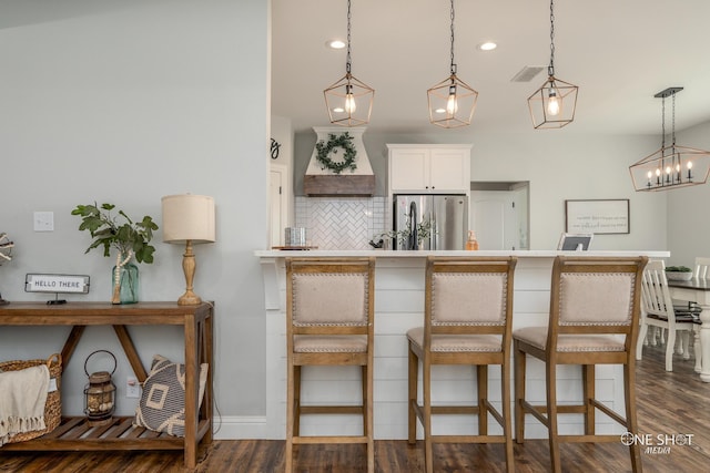 3085 County Road 131, Tuscola, TX 79562 - kitchen with freestanding refrigerator, decorative backsplash, a breakfast bar, wall chimney exhaust hood, and recessed lighting