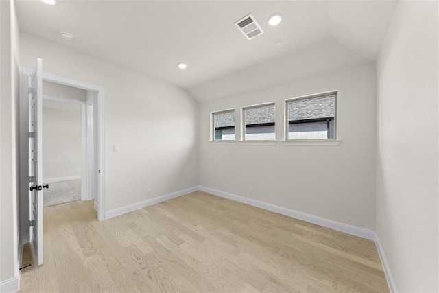 empty room with vaulted ceiling and light wood-type flooring