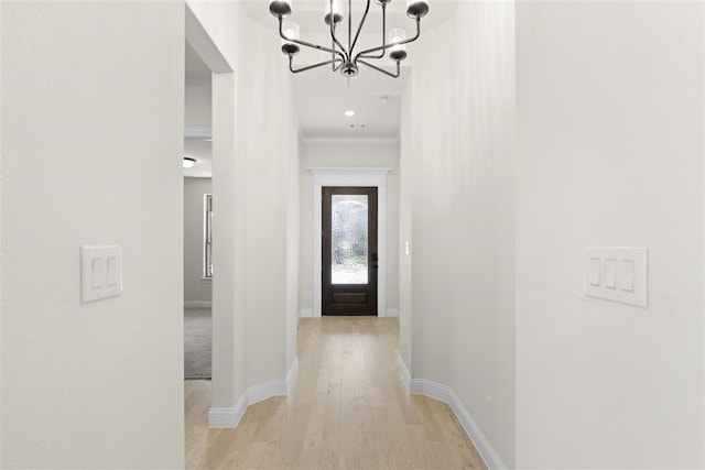 interior space featuring light hardwood / wood-style floors, ornamental molding, and a notable chandelier