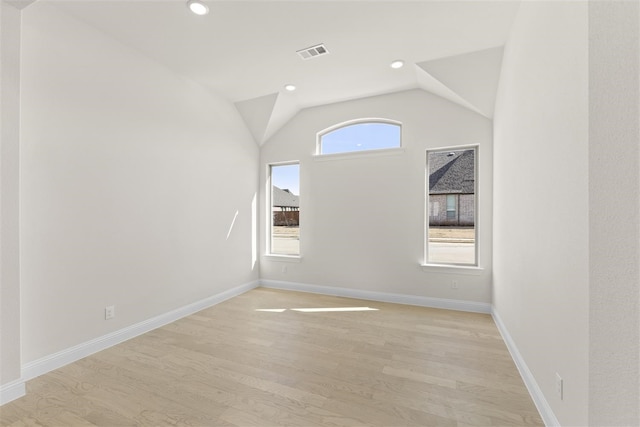 spare room featuring light hardwood / wood-style floors and lofted ceiling