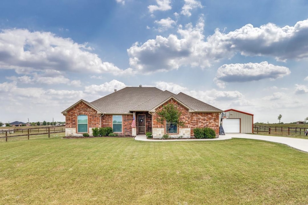 view of front of house featuring brick siding, fence, driveway, and a front lawn