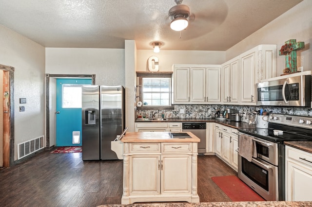 kitchen featuring appliances with stainless steel finishes, backsplash, dark hardwood / wood-style floors, sink, and ceiling fan