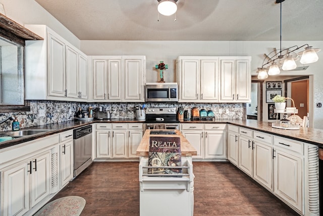 kitchen with ceiling fan, stainless steel appliances, pendant lighting, and dark hardwood / wood-style flooring