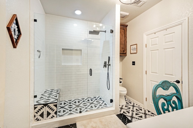 bathroom featuring tile patterned floors, a shower with shower door, and toilet