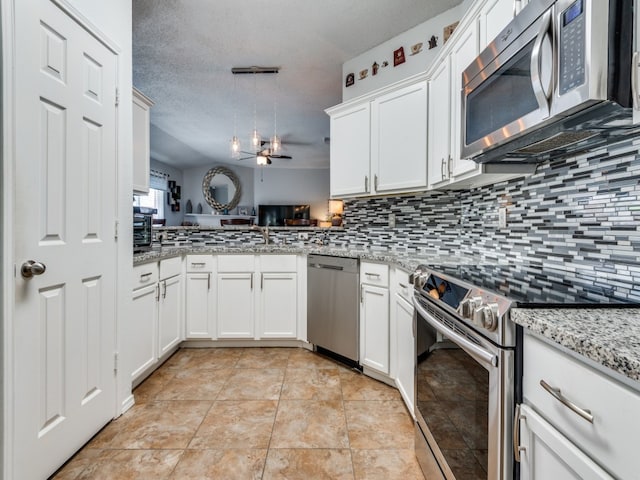 kitchen featuring light tile patterned flooring, appliances with stainless steel finishes, decorative backsplash, a textured ceiling, and kitchen peninsula