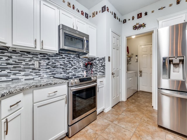 kitchen with appliances with stainless steel finishes, backsplash, washer and clothes dryer, light stone countertops, and white cabinets