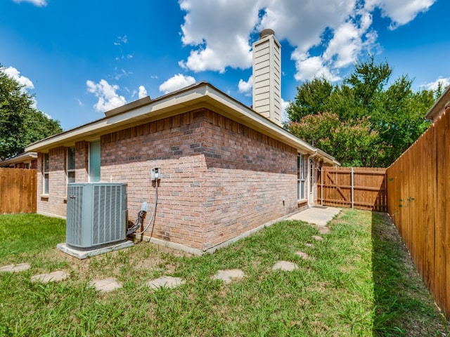 view of side of home featuring central air condition unit and a lawn