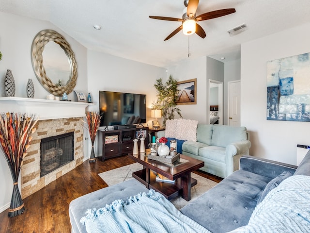 living room with ceiling fan, hardwood / wood-style flooring, and a stone fireplace