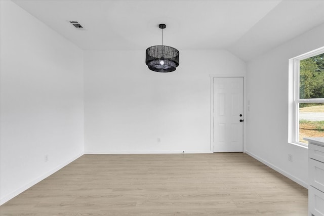 spare room featuring light hardwood / wood-style floors, a wealth of natural light, and vaulted ceiling