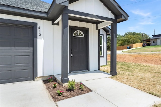 property entrance featuring a garage and a lawn