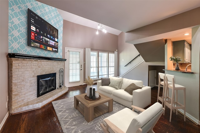 living room featuring dark hardwood / wood-style flooring, a fireplace, sink, and lofted ceiling