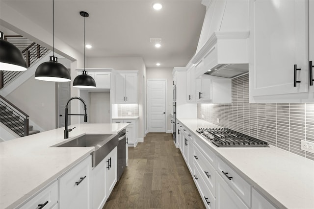 kitchen with white cabinets, dark wood finished floors, decorative light fixtures, stainless steel appliances, and backsplash