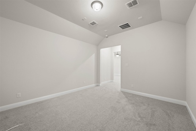 spare room with lofted ceiling, carpet, visible vents, and baseboards