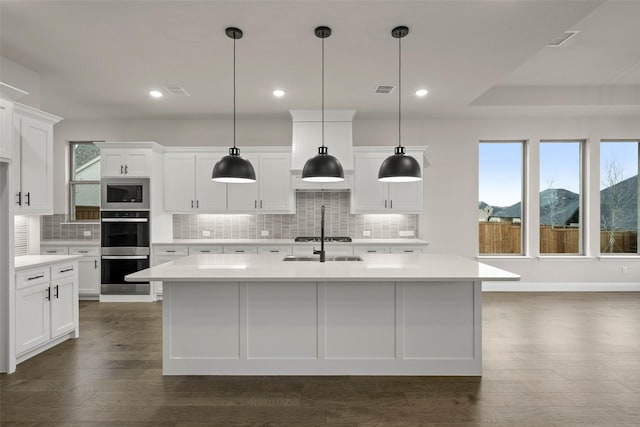 unfurnished living room featuring an inviting chandelier, plenty of natural light, dark wood-style floors, and a sink