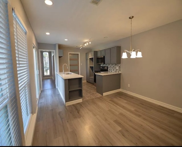 kitchen with electric range, gray cabinets, stainless steel microwave, backsplash, and light wood-style floors